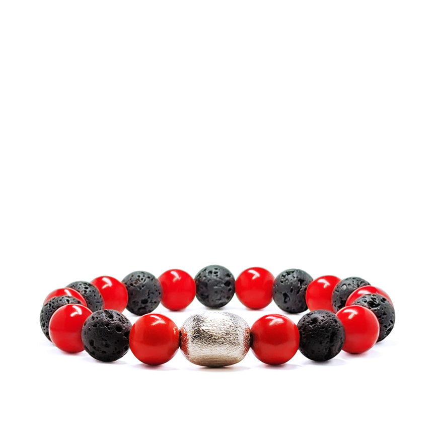 Red coral bracelet with black lava beads and silver accent laying on a white background