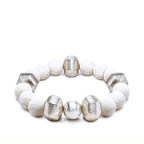 White lava bracelet with alternating silver beads laying on a white background
