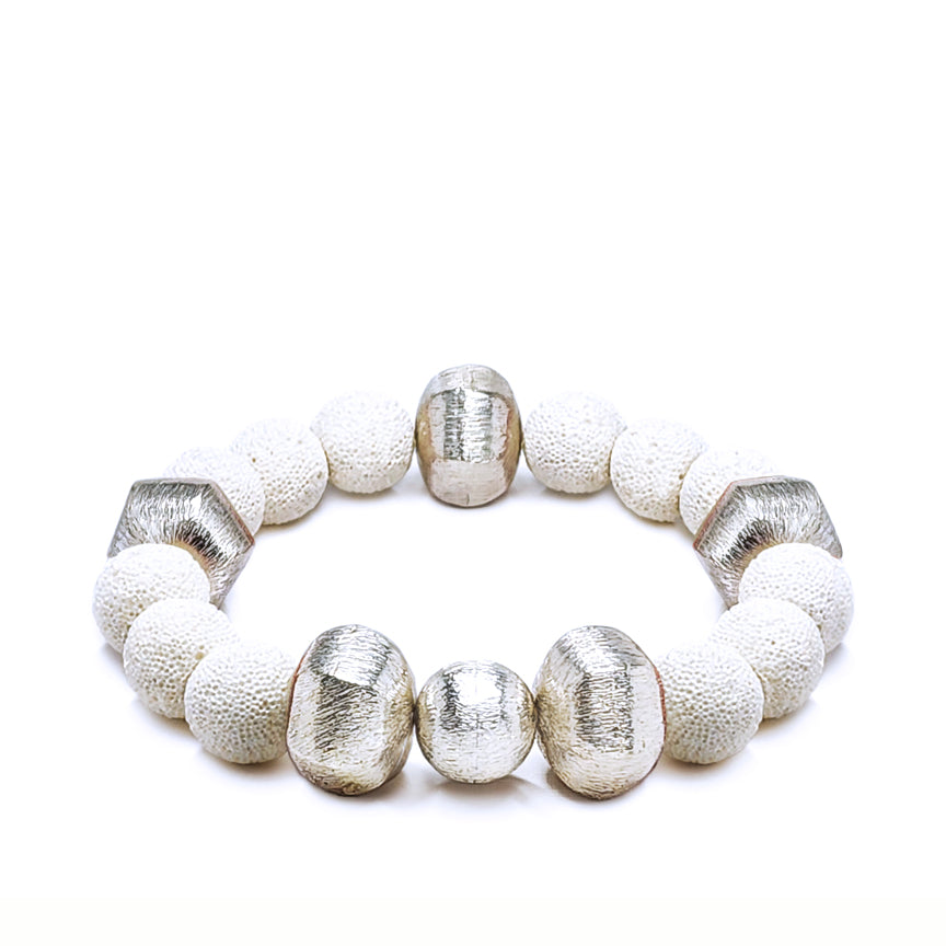 White lava bracelet with alternating silver beads laying on a white background